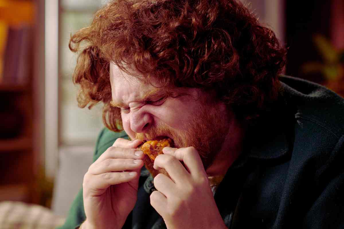 persona con i capelli rossi mangia il pollo
